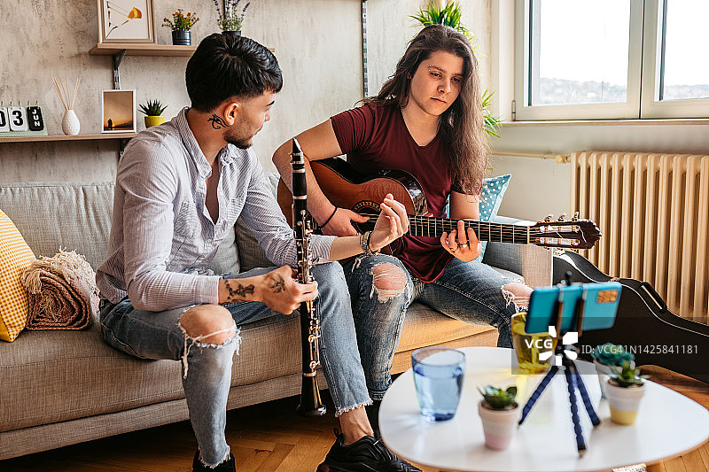 两名男子在家用手机制作单簧管吉他演奏教程图片素材