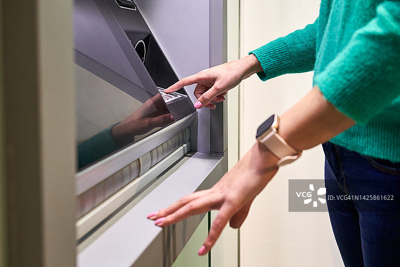女士在ATM机上操作。个人理财与银行概念图片素材