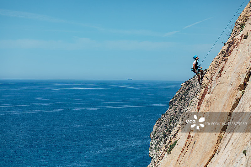 专业男登山者悬挂在陡峭的悬崖上图片素材