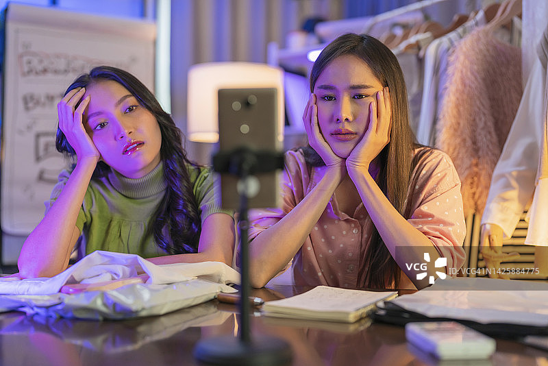 卖不出去衣服的疲惫网店店主，直播带货时头痛。商业焦虑和压力概念。网上购物和营销概念。年轻女商人。图片素材