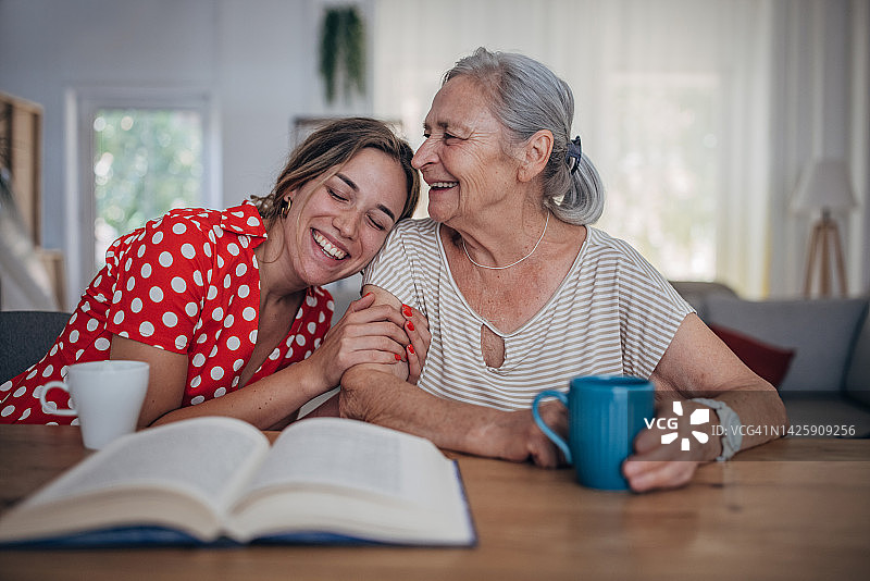 快乐的奶奶和十几岁的孙女在家享受早晨咖啡并交谈图片素材
