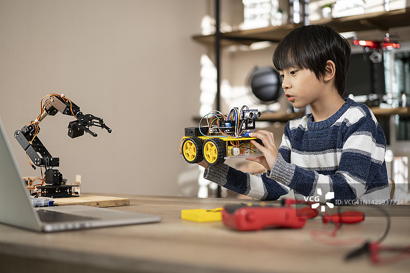专注的男学生定制和修理自动驾驶的机器人汽车图片素材