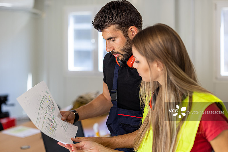 一对年轻的建筑工人在办公室分析项目图片素材