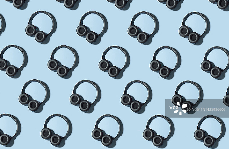 蓝色背景上黑色无线耳机的无缝图案图片素材