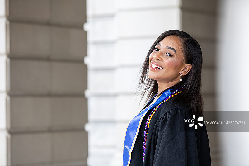 毕业典礼后对着镜头微笑的迷人年轻毕业生图片素材