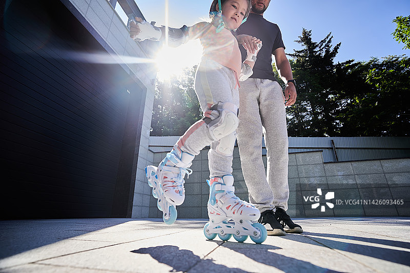 阳光下，父亲教女儿滑旱冰图片素材