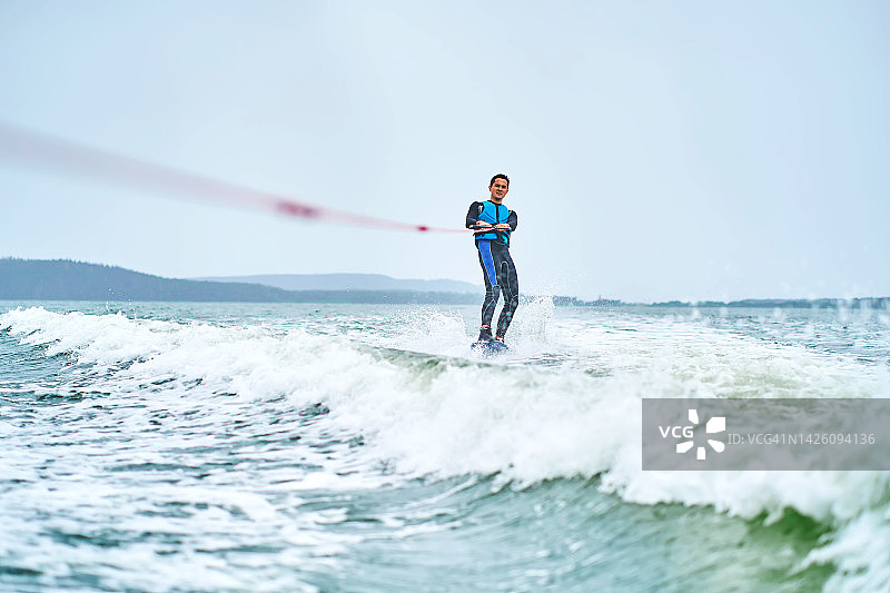 在湖上玩尾波滑水的年轻男人图片素材
