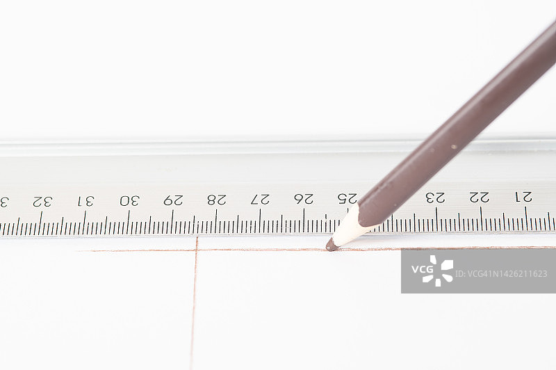 有人在尺子的帮助下在白纸上画一条线。图片素材