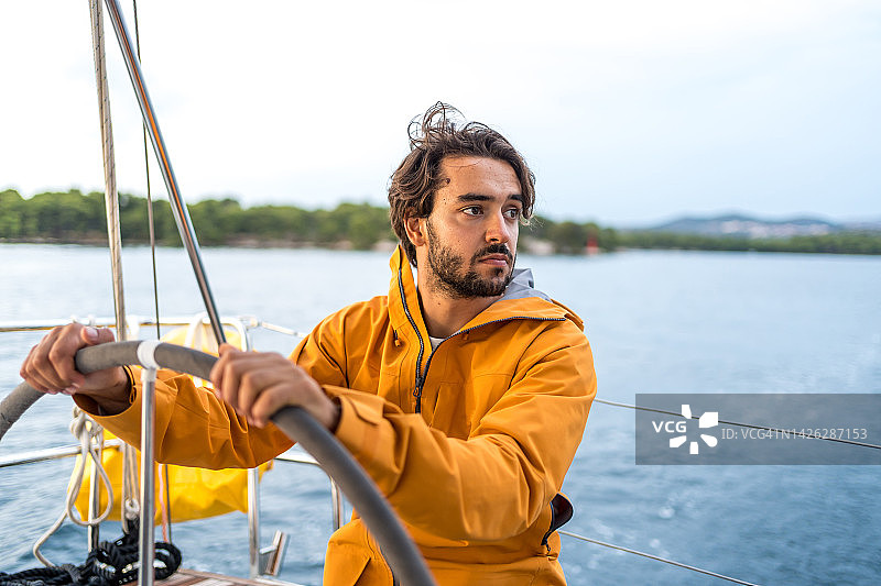 年轻人驾驶帆船在海上图片素材