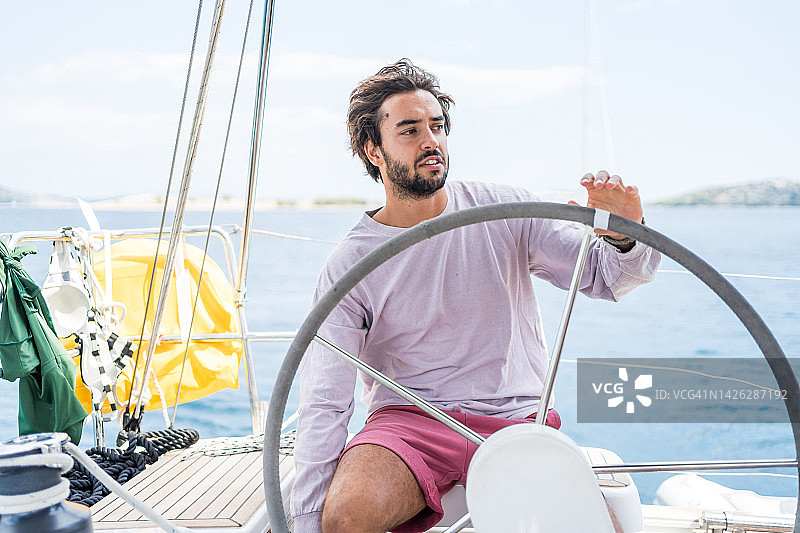 年轻人驾驶帆船在海上图片素材
