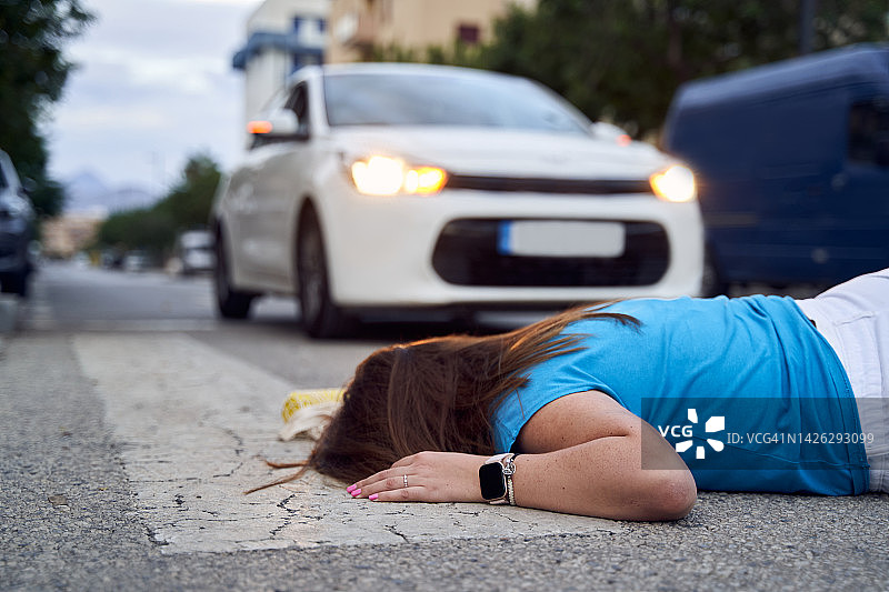 被汽车撞倒在人行横道上的年轻女子图片素材