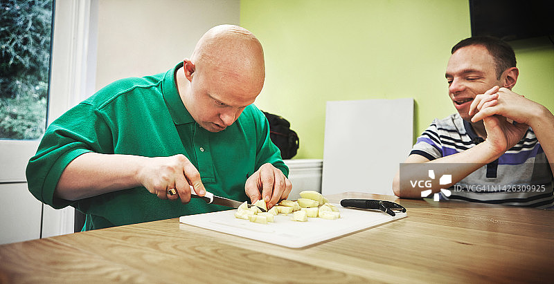 厨房中患有唐氏综合症的残疾人士小组专注于运动技能训练。残疾护理中心的人们通过晚餐食物来练习协调性、平衡性和手部活动能力图片素材