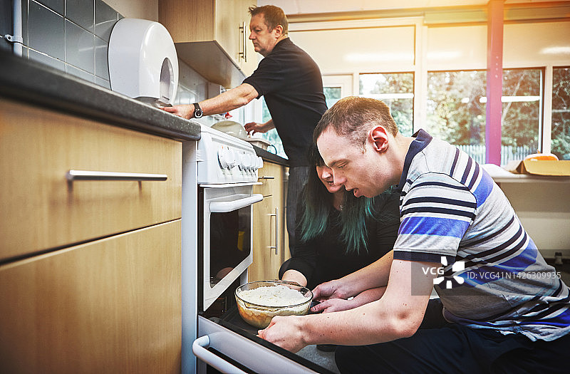 在医疗机构中学习烘焙技能的特殊需求人士：食物、发展与残疾，成熟夫妇帮助唐氏综合征男性，鼓励独立技能图片素材