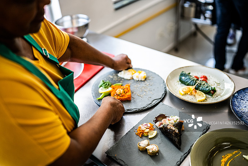 女人在商业厨房的盘子里摆放食物图片素材