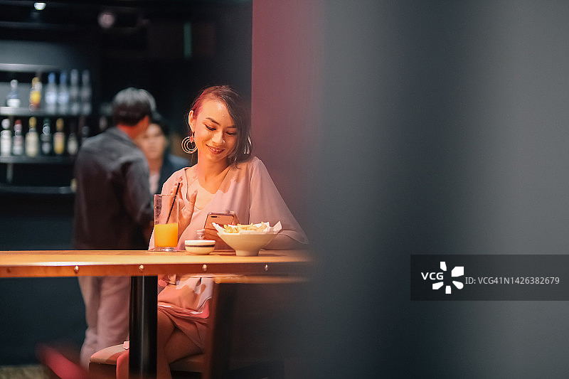 独自在酒吧看手机的女人图片素材