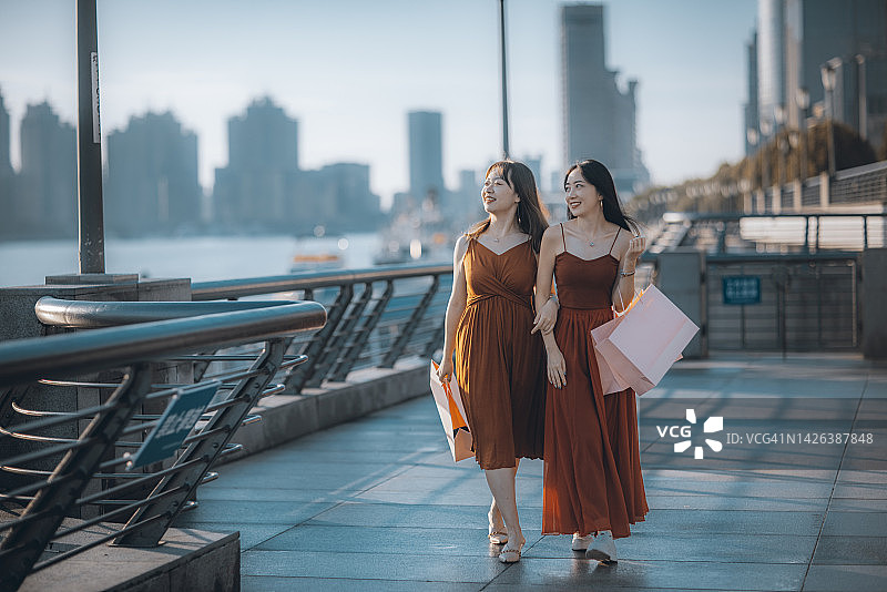 两名快乐的亚洲女性在上海外滩拿着购物袋图片素材