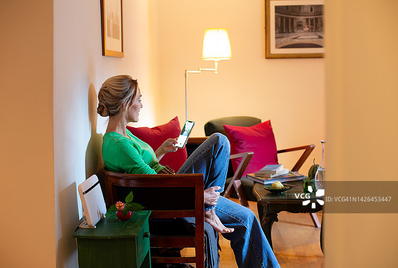 女人坐在沙发上用手机刷社交媒体图片素材