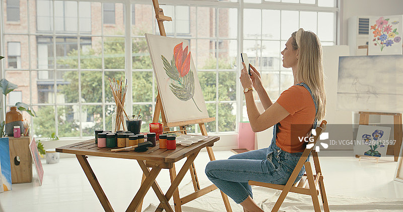 艺术，创意女性绘画并用手机拍照，在社交媒体App、互联网或网站上进行广告和分享。油画家艺术家用智能手机在画布上捕捉绘画作品图片素材