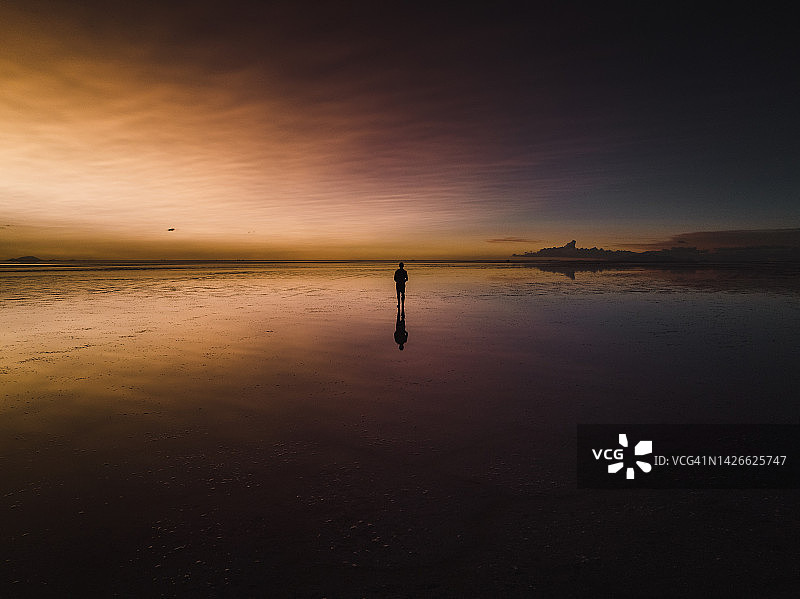 玻利维亚乌尤尼盐沼日落时分的盐滩航拍，一人走在上面图片素材