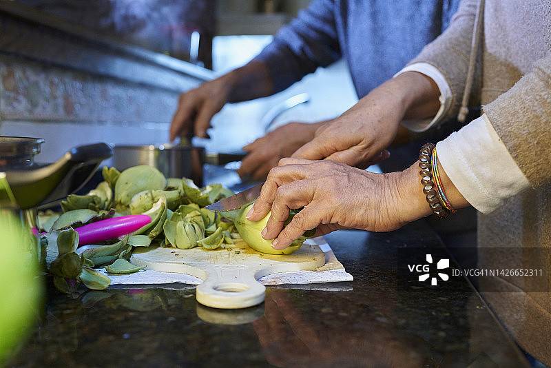 一对夫妇在家准备健康晚餐，女人切菜男人做饭图片素材