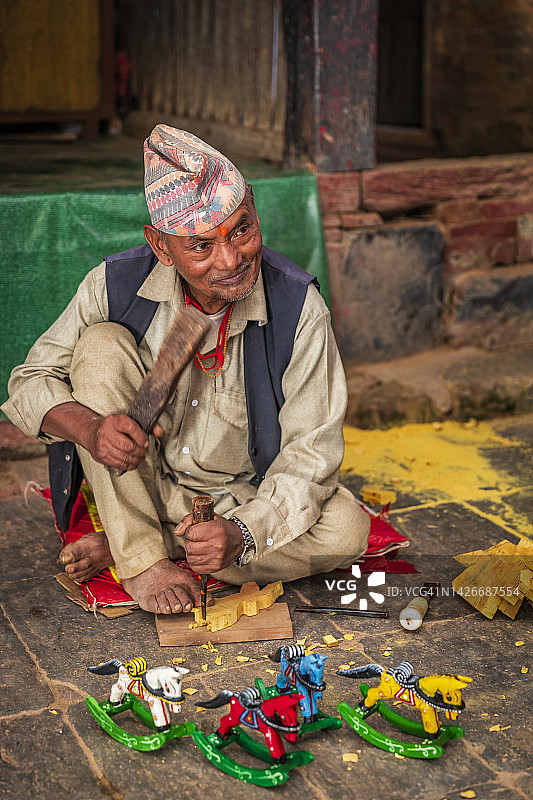 尼泊尔巴克塔普尔古镇制作木摇马的男人图片素材