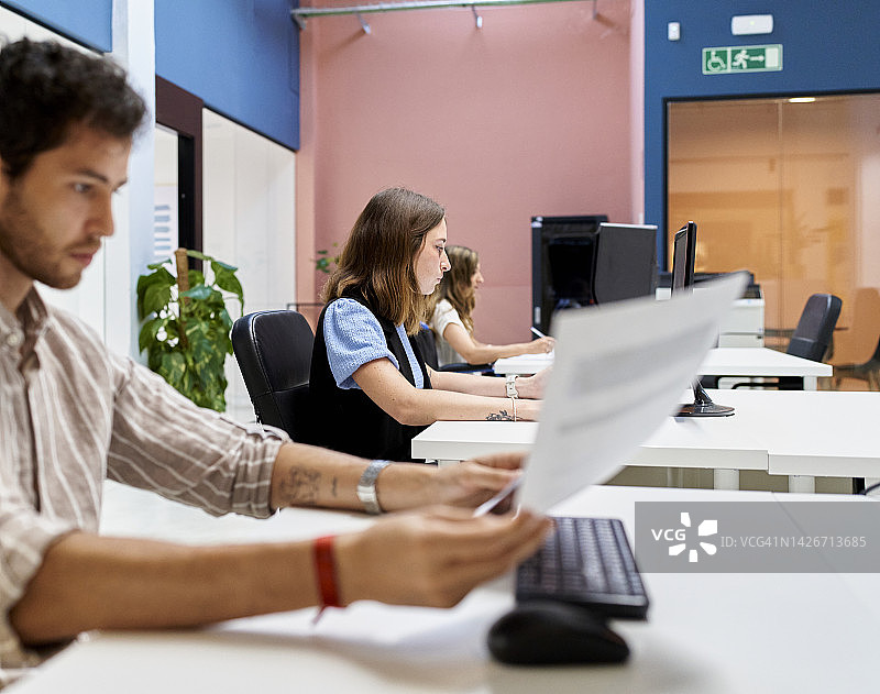 男女数据分析师在办公室使用电脑工作，专注于向系统输入信息图片素材