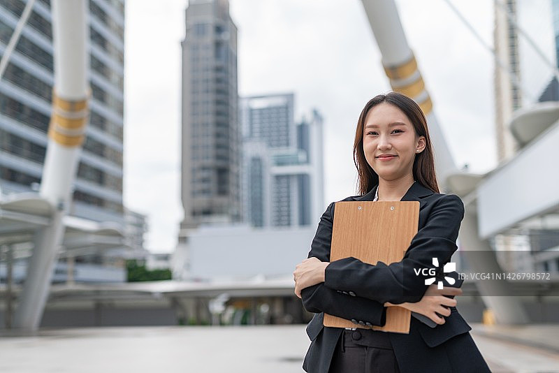 在曼谷中央商务区拿着文件夹和智能手机的亚洲女商人图片素材