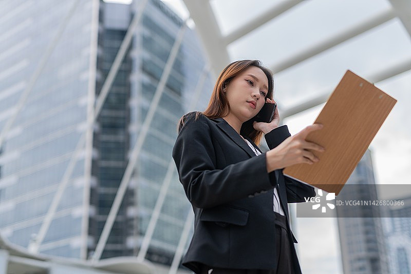 在曼谷市中心商务区查看营销和销售库存报告的迷人年轻亚裔职业女商人图片素材