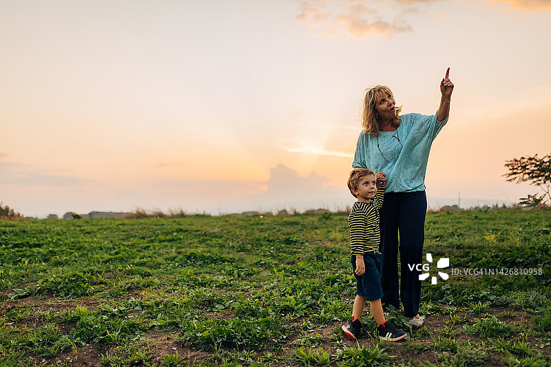 奶奶牵着可爱的孙子的手站在公园里图片素材