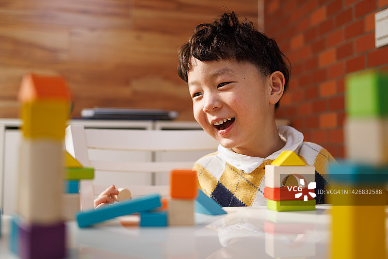 快乐的亚裔男孩在阳台上玩积木图片素材