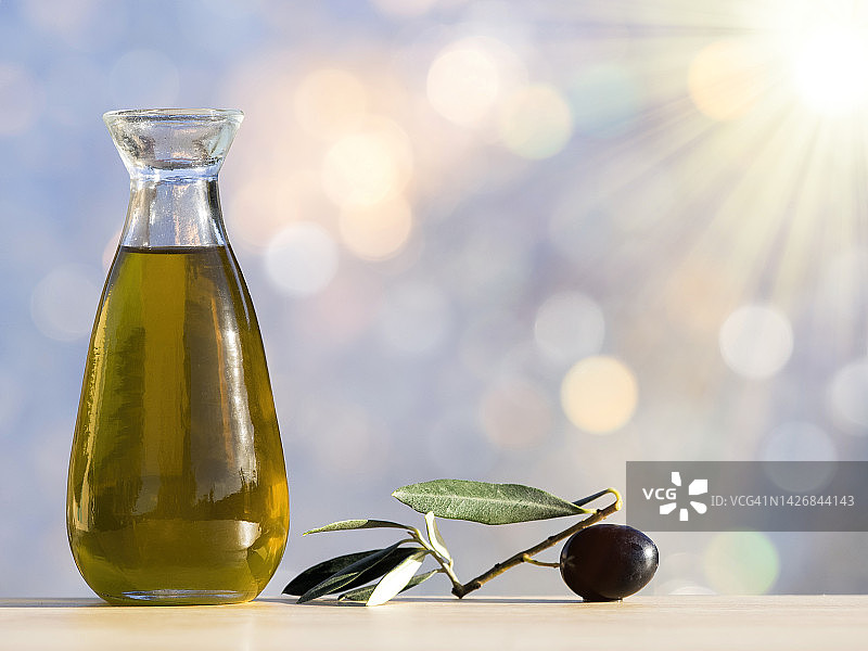 阳光照射下的橄榄油瓶和成熟橄榄图片素材