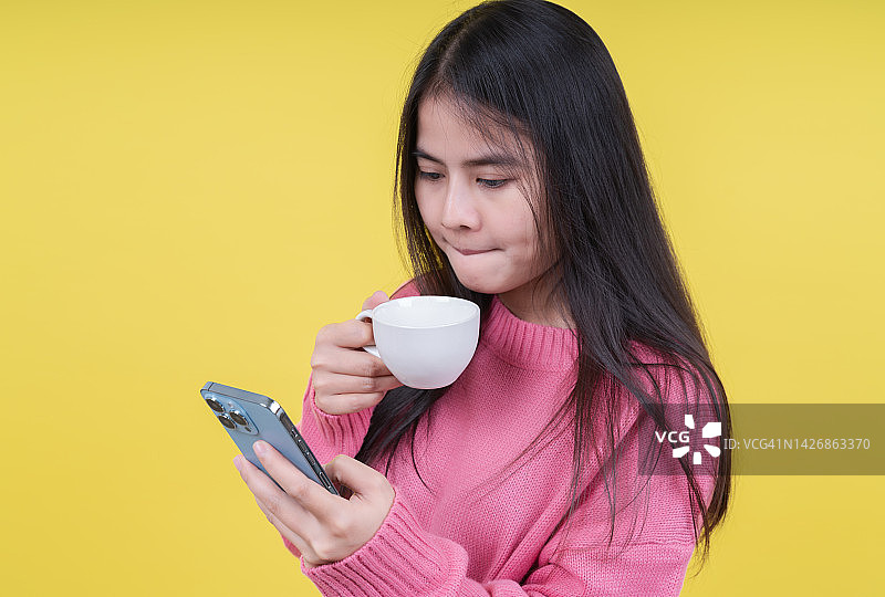 手持咖啡杯的快乐年轻女子使用手机图片素材