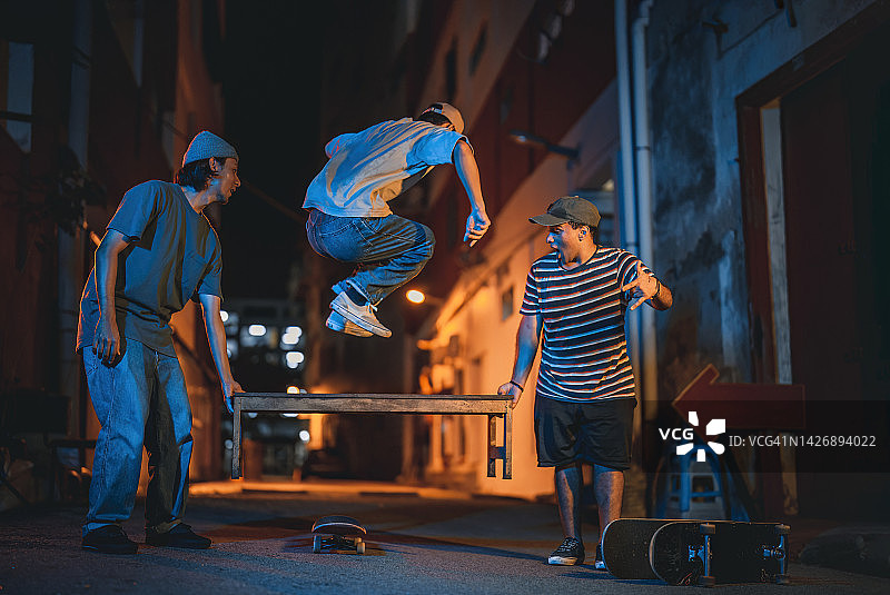 年轻人在后巷与朋友一起玩滑板图片素材
