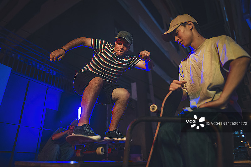 年轻人在后巷与朋友一起玩滑板图片素材