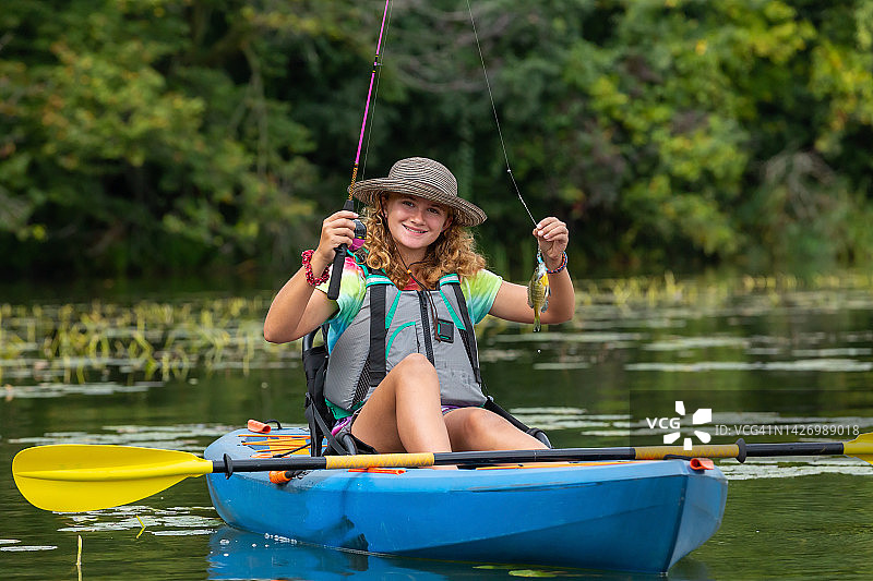 女孩皮划艇钓鱼时举起一条鱼图片素材
