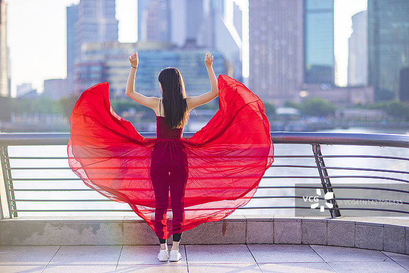 清晨在上海外滩跳舞的红裙年轻漂亮女人图片素材