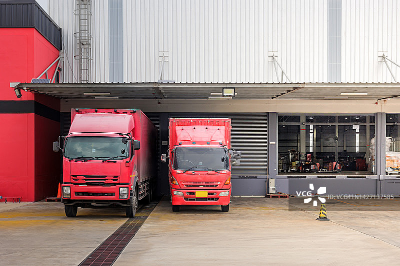 配送或供应概念图：红色卡车在设施装货图片素材