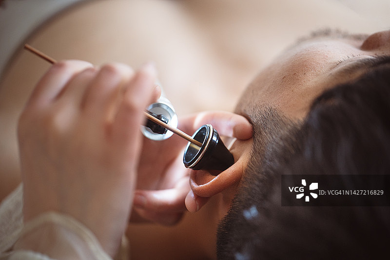 年轻女按摩师为男士提供耳部按摩图片素材