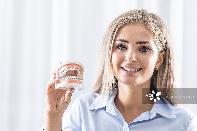 微笑少女手中的牙科隐形牙套或硅胶训练器图片素材