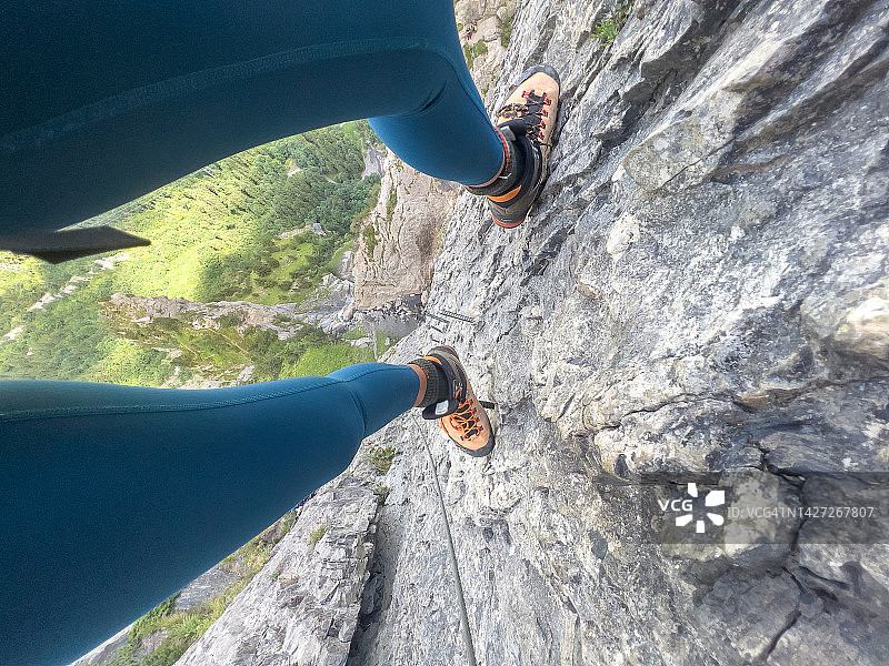 通过铁索攀岩看到的垂直悬崖景观的女性视角图片素材