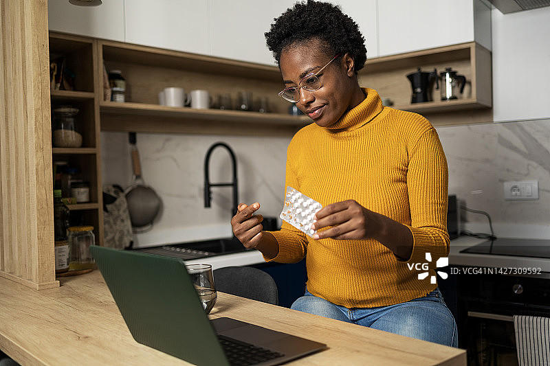 一位非裔美国妇女正在互联网上查找有关她手中药物的信息图片素材