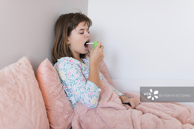 在床上休息并使用吸入器的女孩图片素材