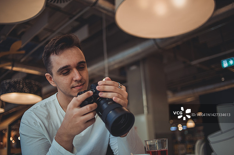男子在咖啡馆用相机拍照图片素材