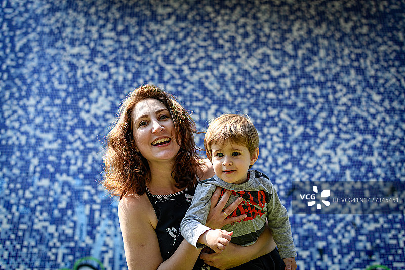 抱着幼儿儿子的年轻母亲肖像图片素材