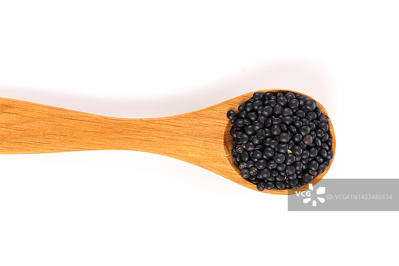 白色背景木勺中的黑色有机小扁豆图片素材