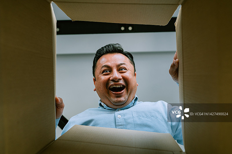 亚洲男子打开纸箱并向内看图片素材
