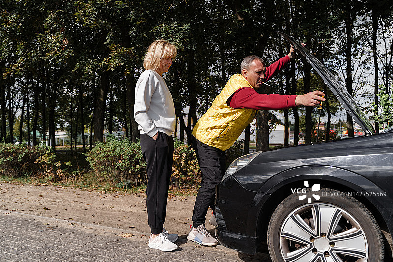 中年妇女和男人一起检查汽车引擎盖下的情况图片素材