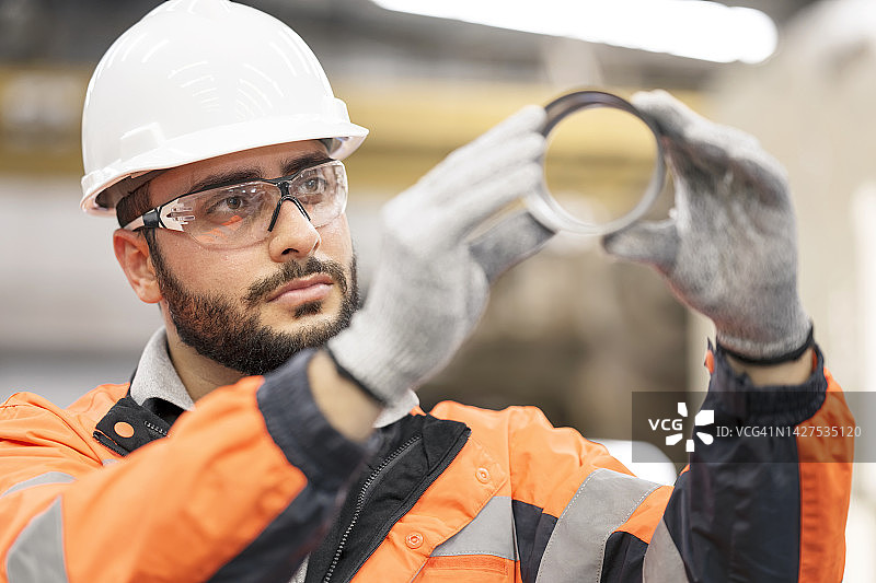 制造业中的集成质量控制和质量管理。男性质量控制工程师在生产线中检查汽车零件，以确保产品整个生命周期的质量标准。图片素材
