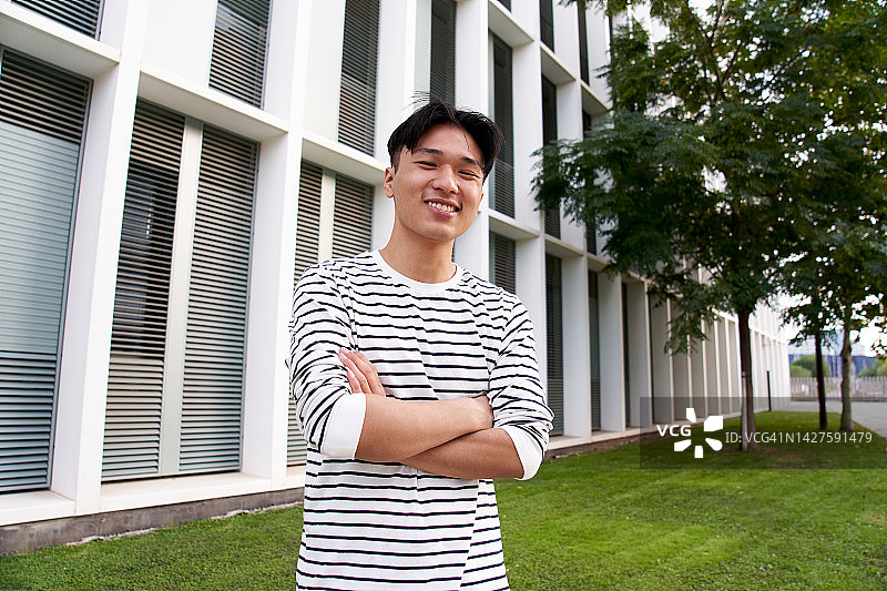 亚洲年轻男子肖像摄影，面带微笑，双手交叉于胸前图片素材