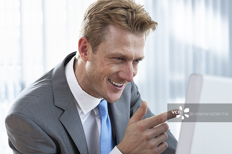 中年商人指着屏幕，享受他完美的商业理念图片素材